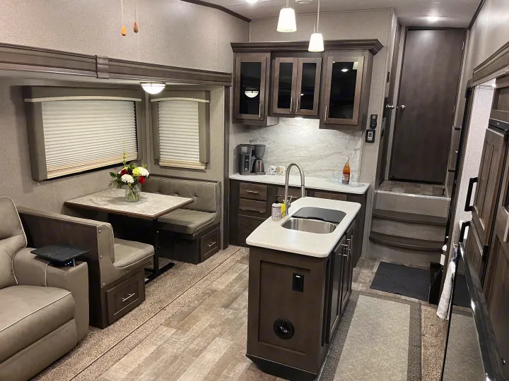 Inviting rv rental interior featuring a full kitchen, comfortable dining area, and plush seating in neutral tones.. Forest River Rockwood Ultra Lite 2020