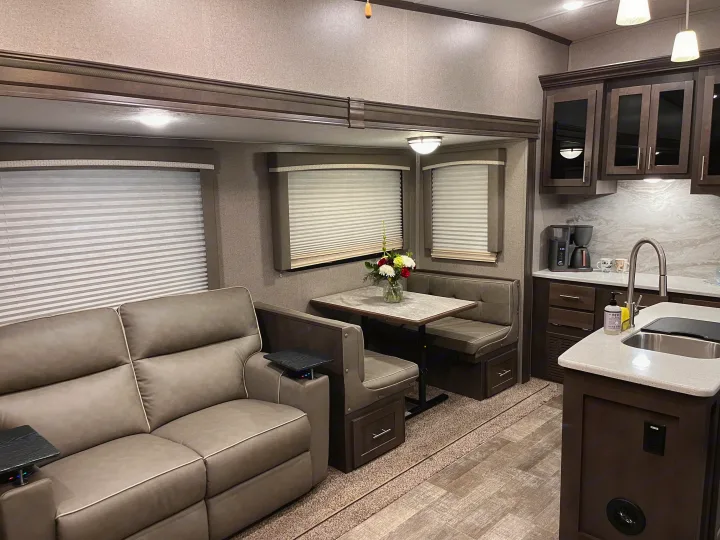 Modern rv rental interior with a comfortable sofa, dining booth, and full kitchen, ideal for travel comfort.. Forest River Rockwood Ultra Lite 2020