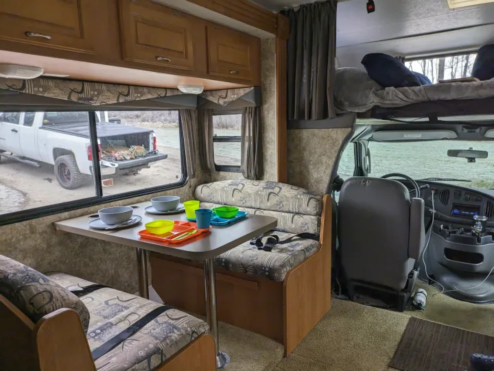 RV rental interior with dinette, bunk, and cab view, showing a truck outside.. Coachmen Freelander Deluxe/Premier 2005