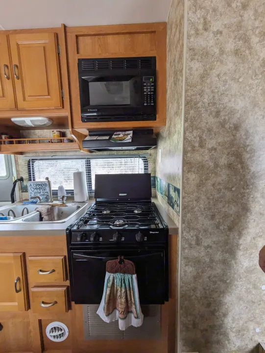 This RV rental kitchen features wood cabinets, a Dometic microwave, Magic Chef stove, and sink. Perfect for camping trips!. Coachmen Freelander Deluxe/Premier 2005