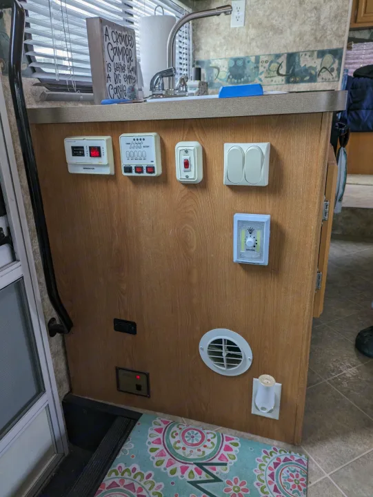 RV rental interior: kitchen with sink, controls for generator/tanks/water heater, plus a 'crowded camper' sign.. Coachmen Freelander Deluxe/Premier 2005