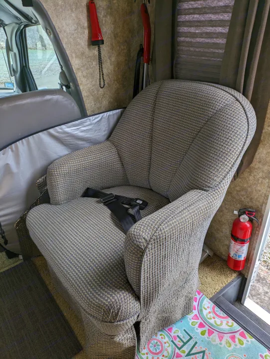 Interior of an RV rental: a large, patterned armchair with a seatbelt and a fire extinguisher nearby for safety.. Coachmen Freelander Deluxe/Premier 2005