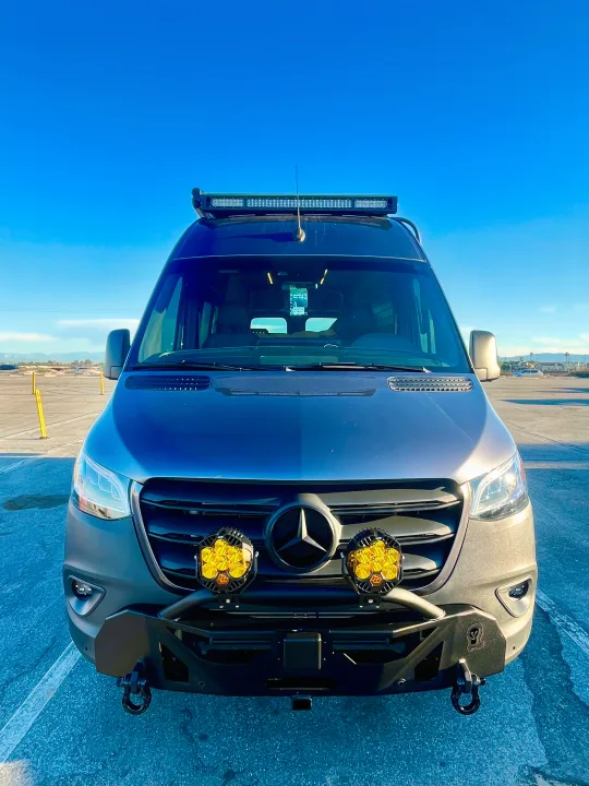 A modified Mercedes Sprinter camper van, equipped with custom lights & bumper, available for rv rental, under a clear sky.. Mercedes-Benz Sprinter 2021
