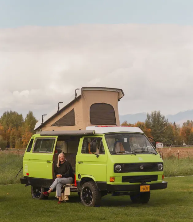 Lime green VW Vanagon camper. Ideal for RV rental, this van life scene shows a woman relaxing inside.. Volkswagen Westfalia 1984