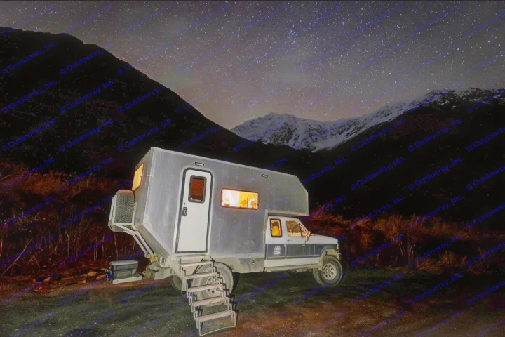 Night sky astrophotography with a unique RV rental. Custom camper lights up a dark mountain landscape under a starry sky.. Ford F250 1997