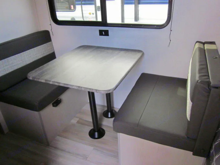 Inside this RV rental, a comfortable dinette features a light gray table and two dark gray benches, ready for meals.. Coachmen Clipper 2024