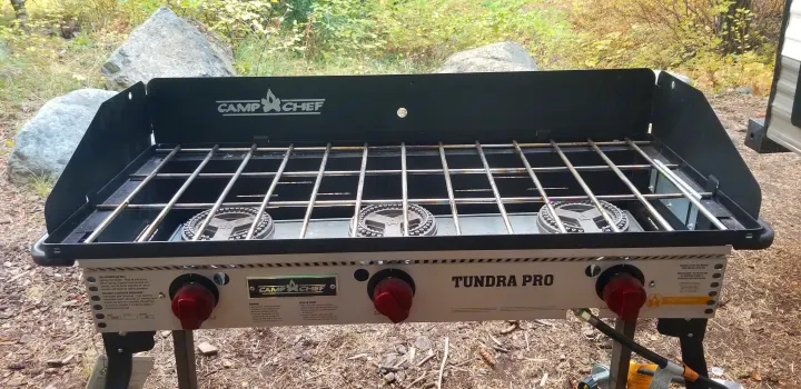 A Camp Chef Tundra Pro 3-burner gas stove with black and silver grates, ideal for outdoor cooking on an rv rental vacation.. Jayco Jay Flight SLX 2019