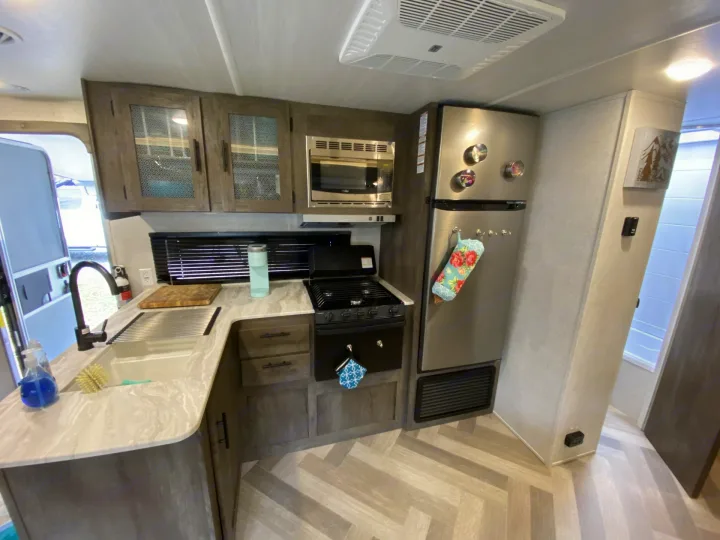 Explore this modern RV rental's compact kitchen, featuring a sink, stove, microwave, and refrigerator.. Forest River Salem Cruise Lite 2022
