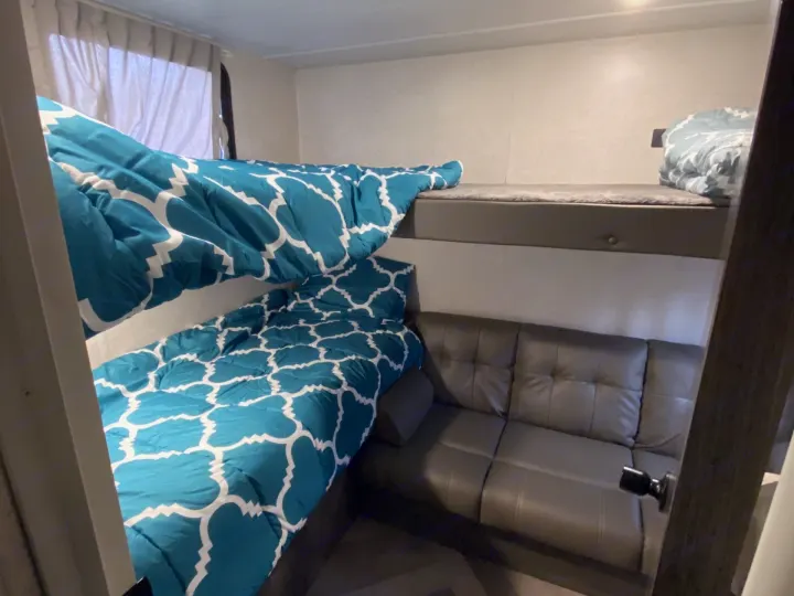RV rental showing bunk beds with blue comforters and a grey sofa inside.. Forest River Salem Cruise Lite 2022