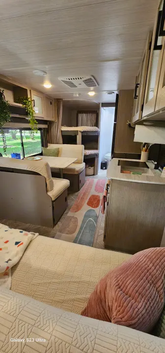 Cozy RV rental interior featuring a dinette, bunk beds, and a compact kitchen, ideal for family travel.. Forest River Wildwood X-Lite Platinum 2024