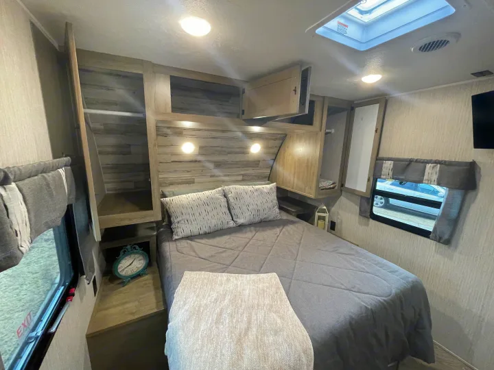 Comfortable RV rental bedroom with ample storage, a queen bed, skylight, and inviting decor, perfect for mobile adventures.. Forest River Palomino Puma 2023