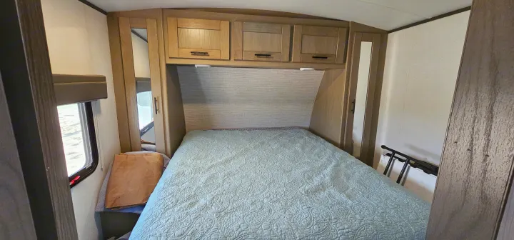 Cozy RV bedroom interior featuring a comfortable bed, overhead cabinets, and a window, ideal for an RV rental adventure.. Cruiser RV Shadow Cruiser 2021