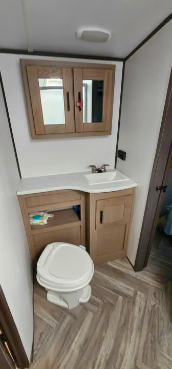 Compact RV rental bathroom featuring a sink, toilet, vanity, and medicine cabinet. Clean, functional travel interior.. Cruiser RV Shadow Cruiser 2021