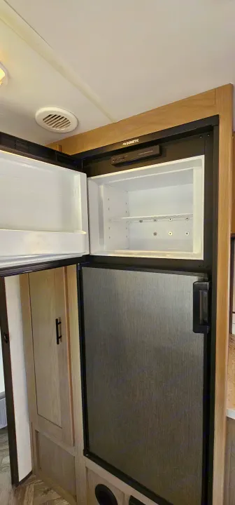 This RV rental offers a Dometic refrigerator: its empty top freezer is open, while the bottom fridge remains closed.. Cruiser RV Shadow Cruiser 2021