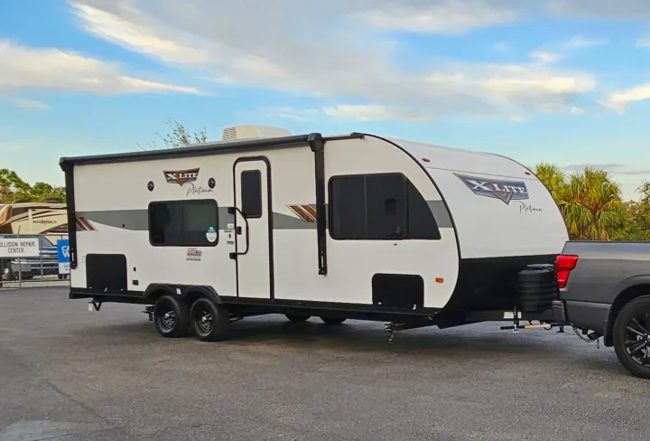 A white X Lite Platinum travel trailer is hitched to a grey pickup truck, ideal for your RV rental needs.. Forest River Wildwood X-Lite Platinum 2024