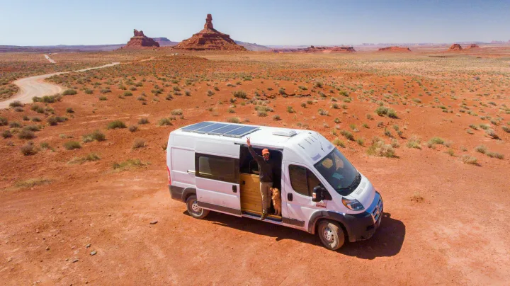 RV rental camper van with solar panels, man & dog in a vast red desert landscape.. Dodge Sprinter Van 2016