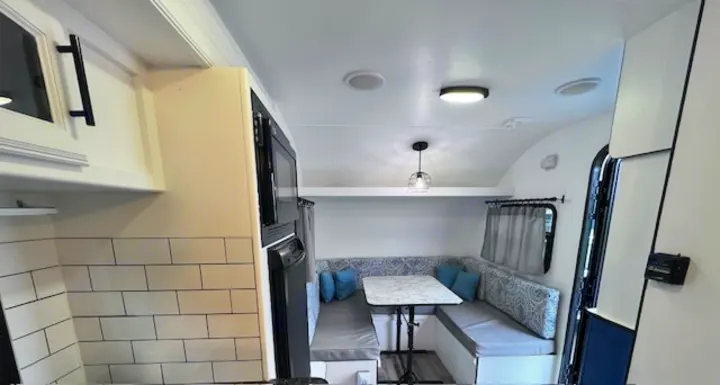 Bright, modern RV rental interior featuring a compact kitchen & comfy U-shaped dinette. Perfect for your next adventure!. Winnie Drop Winnie Drop Trailer 2017
