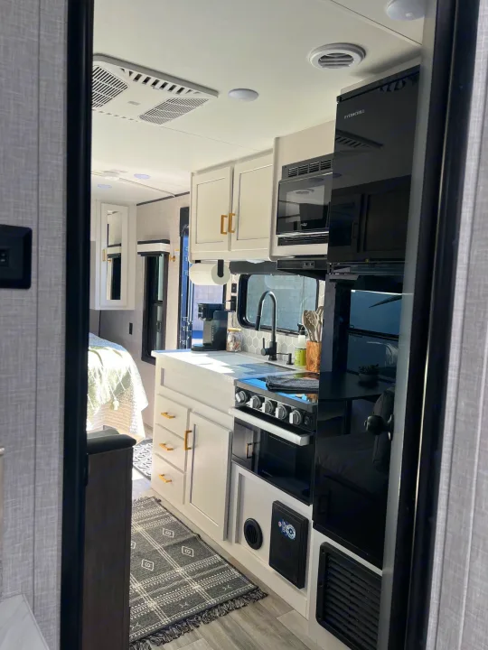 Step inside this RV rental: a bright, modern kitchen with all the essentials and a glimpse of the comfy bedroom.. Jayco 224BHW 2024