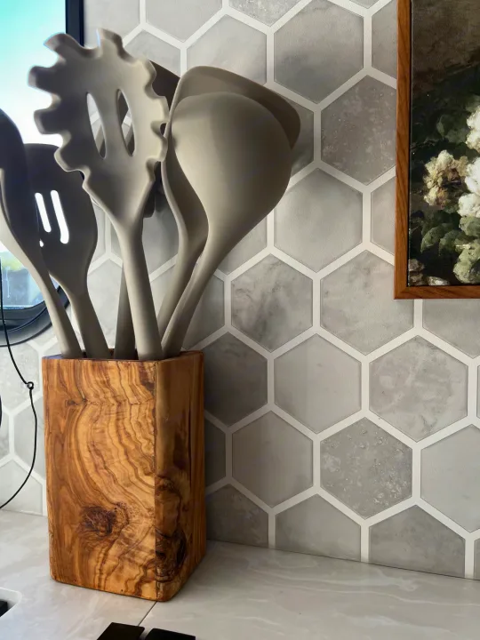 Modern RV rental kitchen setup with gray silicone utensils in a rustic wood holder against a hexagonal tiled backsplash.. Jayco 224BHW 2024