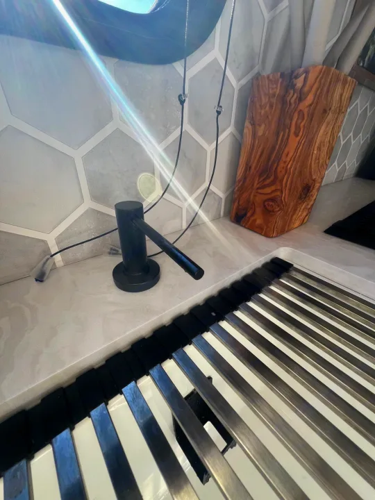 RV rental kitchen area featuring a sink with a drying rack, black soap dispenser, and stylish hexagon tile backsplash.. Jayco 224BHW 2024
