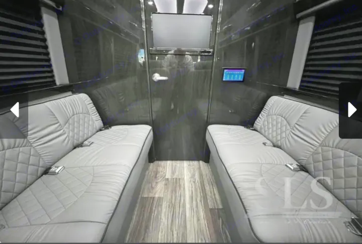 Luxury RV rental interior featuring facing gray benches, wood floor, and a mounted screen for travel comfort.. Midwest Automotive Designs Day Cruiser 2024