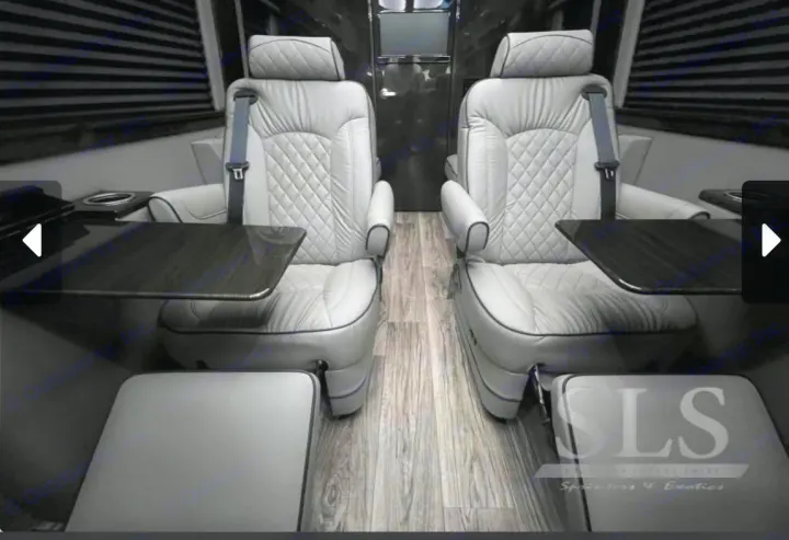 Experience luxury in this RV rental's lavish interior: light gray captain's chairs with tables & footrests for premium travel.. Midwest Automotive Designs Day Cruiser 2024