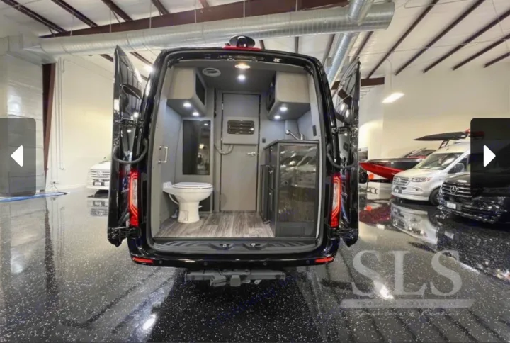 Inside a black luxury camper van, ideal for RV rental. Features a compact bathroom with toilet and a kitchenette with sink/fridge.. Midwest Automotive Designs Day Cruiser 2024