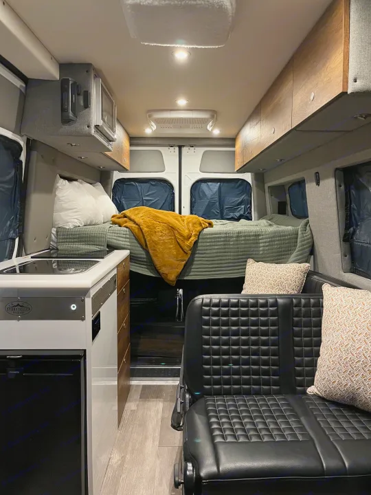 RV rental interior: cozy bed, compact kitchen, and comfy seating inside a modern camper van.. Storyteller Overland Storyteller Overland Class B 2020