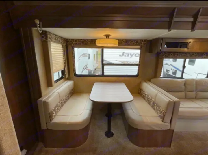 RV rental interior with a cozy dinette, featuring opposing benches, a table, and an adjacent living area with a sofa.. Dutchmen Coleman Light 2018