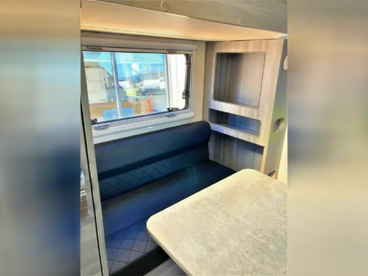Spacious RV rental interior featuring a comfortable dinette with bench seating, a table, and convenient built-in shelving.. OBI OBI Popup Trailer 2022