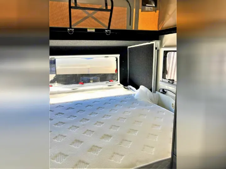 RV rental interior: A comfortable bedroom with a large, white patterned mattress and windows, ready for your next adventure.. OBI OBI Popup Trailer 2022