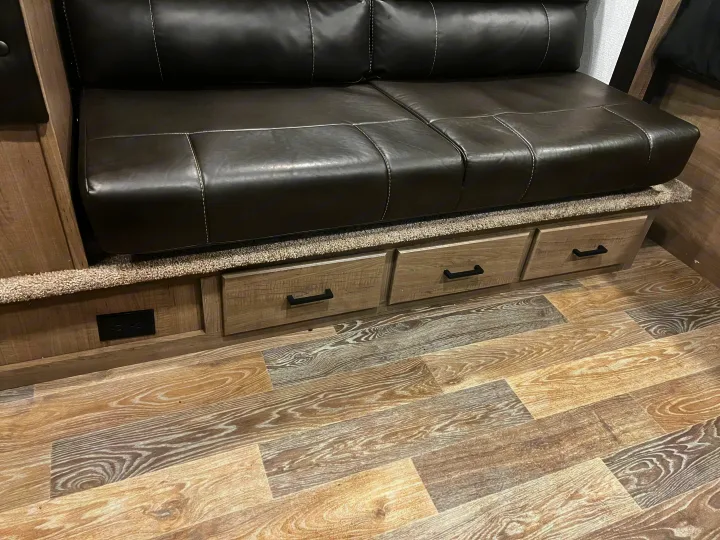 RV rental: Faux leather sofa with built-in storage drawers & outlet, on wood-look flooring.. Keystone RV Hideout 2021
