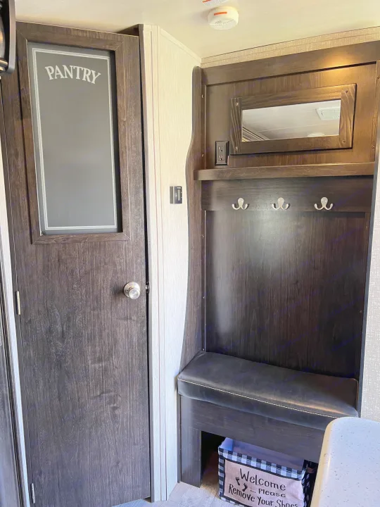 Inside an rv rental: functional pantry door, entryway with bench, hooks, and a 'remove shoes' bin. Compact living.. Heartland RVs North Trail 2018