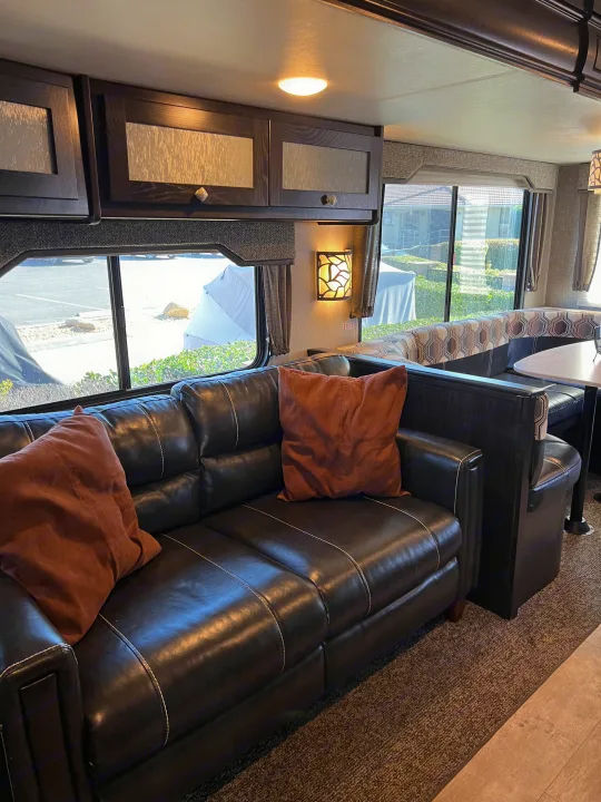 RV rental: Interior showcasing a dark leather sofa, built-in dinette, modern wood cabinetry, and large windows.. Heartland RVs North Trail 2018
