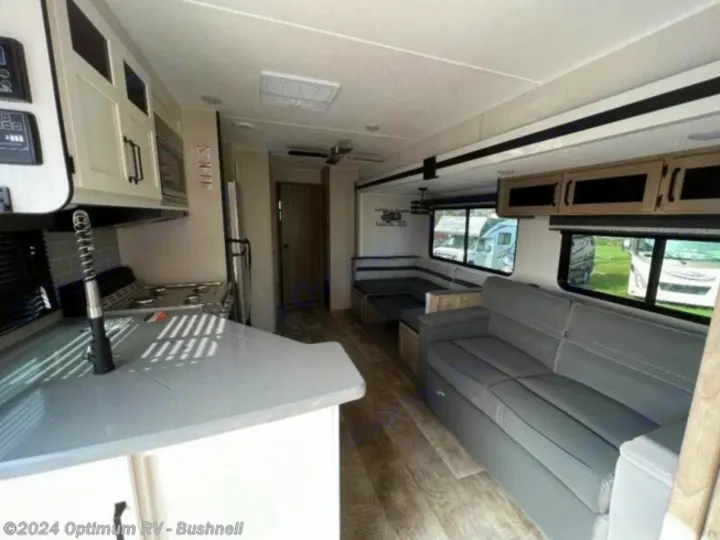 Inside a modern RV rental, showing the bright kitchen with gray counters, a plush sofa, and U-shaped dinette. Hardwood flooring.. Forest River Palomino Puma 2022