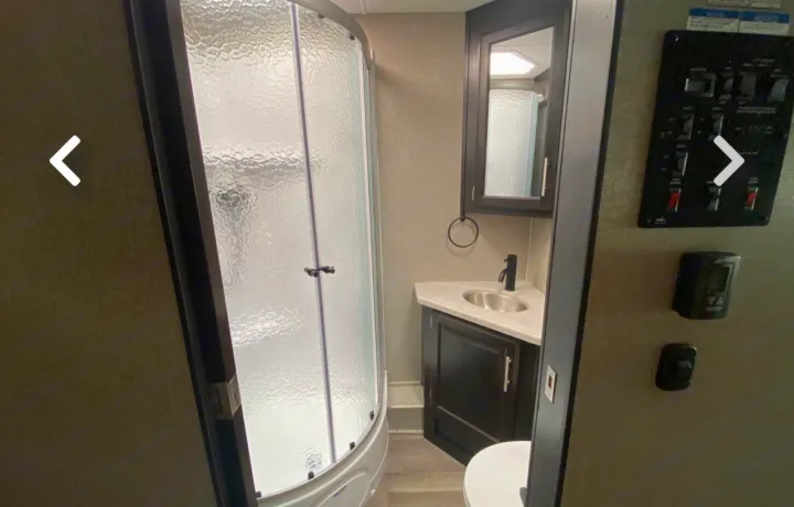 Inside an RV rental: a functional bathroom with a compact shower, corner sink vanity, and built-in control panel for convenience.. Jayco Precept 2021