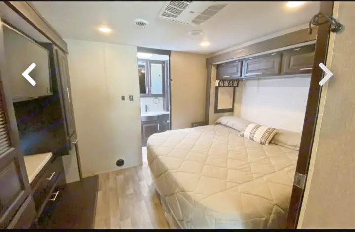 RV rental bedroom: Features a comfortable bed, overhead cabinets, built-in dresser, and en-suite bathroom view.. Jayco Precept 2021