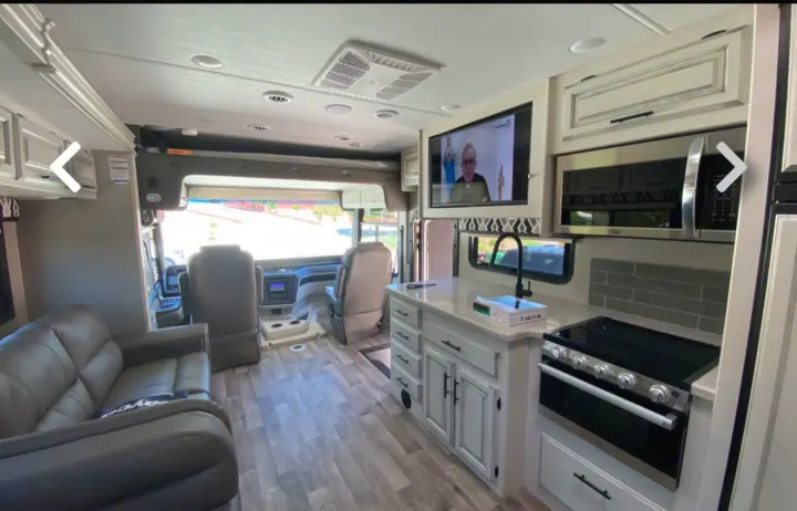 Spacious RV rental interior with a modern kitchen, full living area including a sofa, and bright cockpit view.. Jayco Precept 2021