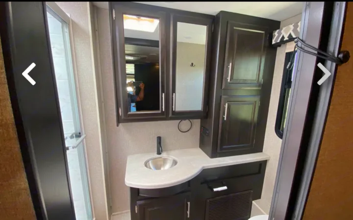 Modern RV rental bathroom features a compact shower, vanity sink, and ample storage cabinets.. Jayco Precept 2021