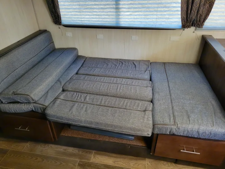 RV rental: Gray upholstered RV dinette sofa with storage, configured as a sleeping area under a window.. Forest River Cherokee Grey Wolf 2019