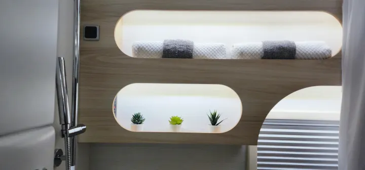 Modern RV rental bathroom: shower, illuminated shelves with fresh towels & decorative succulents for comfort.. Nucamp Tab 400 2024