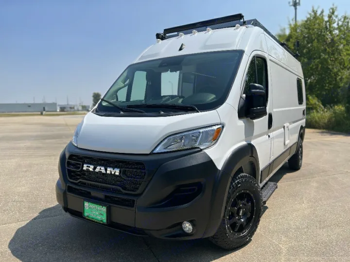 Custom white Ram ProMaster van for RV rental, featuring off-road tires & roof rack.. 27North 27North Class B 2023