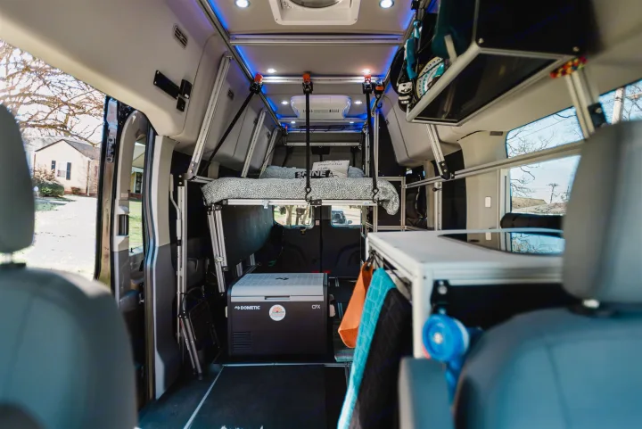 Spacious rv rental camper van interior with an elevated bed, Dometic fridge, and a functional kitchenette for travel.. Ford Transit 350 HD XLT 2019