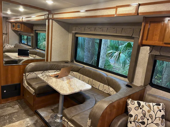 RV rental interior: A comfy dinette with a laptop, perfect for remote work or relaxing on your travels.. COACHMEN LEPRECHAUN 2019