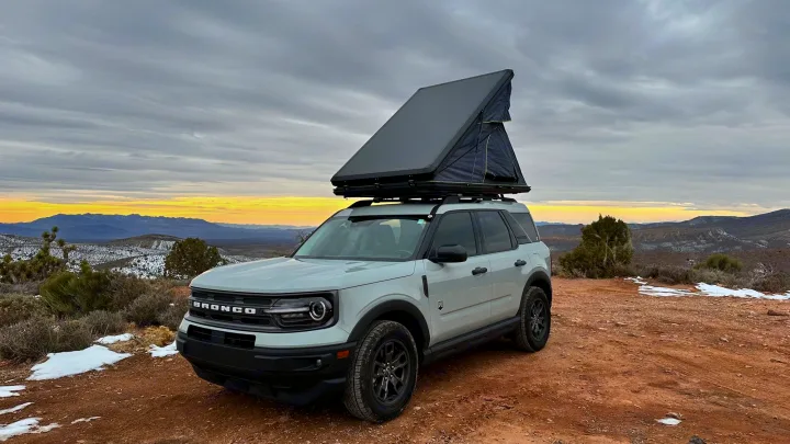 A light gray Bronco Sport with a rooftop tent, parked on a snowy mountain dirt road. Great RV rental alternative!. Ford Bronco Sport 2022