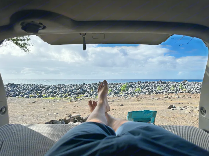 Peaceful ocean view from an RV rental. Feet up, looking out at a rocky beach and the sea under cloudy skies.. Toyota Other 2006