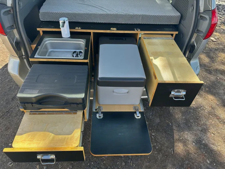 Compact camper setup in an **rv rental**. Features a pull-out kitchen with sink, portable stove, fridge, and storage. Ideal for adventure.. Toyota Other 2006