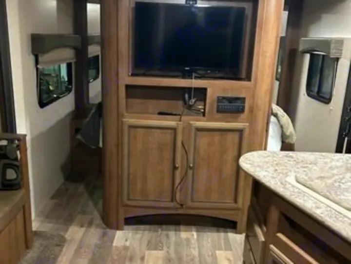 Inside this modern RV rental: a central entertainment unit, kitchen counter, and comfortable living space for camping trips.. Heartland RVs Sundance XLT 2016