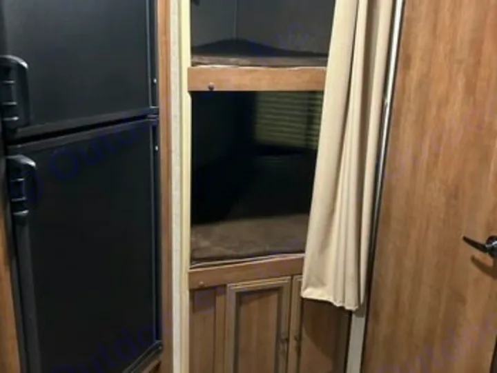 This RV rental interior features a black refrigerator on the left, bunk beds in the center corner, and a curtain on the right.. Heartland RVs Sundance XLT 2016