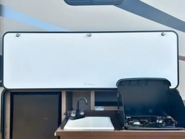This RV rental boasts a full outdoor kitchen, featuring a sink, two-burner stove, and mini-fridge, perfect for camping adventures.. Heartland RVs Sundance XLT 2016